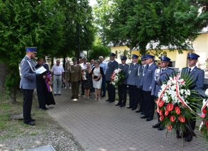 Fotografia kolorowa przedstawiająca policjantów z wieńcem oraz inne osoby które biorą udział w uroczystości 21. rocznicy śmierci gen. Marka Papały.