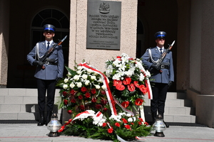 policjanci stojący pod tablicą przy komendzie wojewódzkiej policji w Rzeszowie