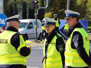 3 policjantow w zoltych kamizelkach rozmawia na skrzyzowaniu