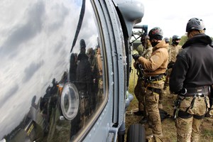 Zamaskowany kontrterrorysta mocuje liny w helikopterze