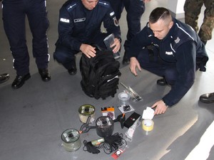 policjanci pirotechnicy kucają przy plecaku z wyposażeniem