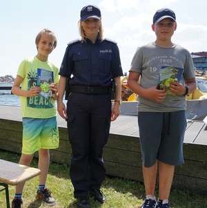 Policjantka z dwoma uczniami, którzy prawidłowo odpowiedzieli na pytania konkursowe