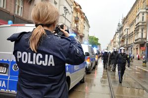 zdjęcie przedstawia umundurowaną policjantkę katowickiego zespołu prasowego, która fotografuje formujących się w szyk stróżów prawa
