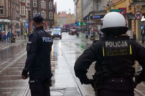 na zdjęciu umundurowani policjanci zabezpieczający przemarsz kibiców