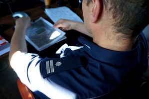 na zdjęciu pagon umundurowanego policjanta, przeglądającego plan zabezpieczenia meczu