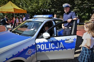 Zdjęcie. Festyn na boisku szkolnym, widoczni policjanci i dzieci oraz policyjny sprzęt
