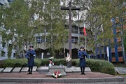 Zdjęcie. Warta honorowa dwóch umundurowanych policjantów z bronią długą przed Grobem Policjanta Polskiego, widoczny również grób i krzyż, w tle rotunda komendy