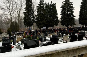 cmentarz oraz uczestnicy uroczystości pogrzebowych w tle