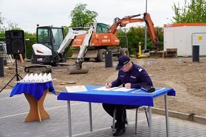 Na zdjęciu Zastępca Komendanta Głównego Policji nadinsp. Dariusz Augustyniak podpisujący akt erekcyjny w tle plac budowy i maszyny budowlane.