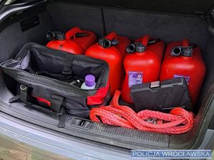Wnętrz bagażnika samochodowego, a w nim czerwone kanistry plastikowe.