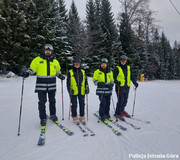 Czterech policjantów na nartach, stojący na stoku.