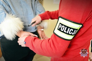 Policjant zapina kajdanki na rękach kobiety