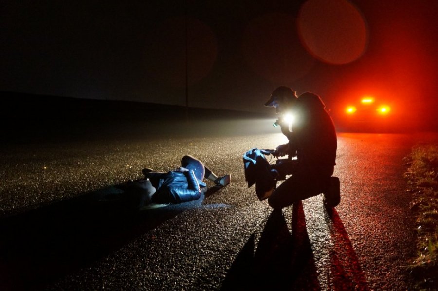 kadr z filmu mężczyzna leżący na drodze drugi mężczyzna sprawdza jego stan