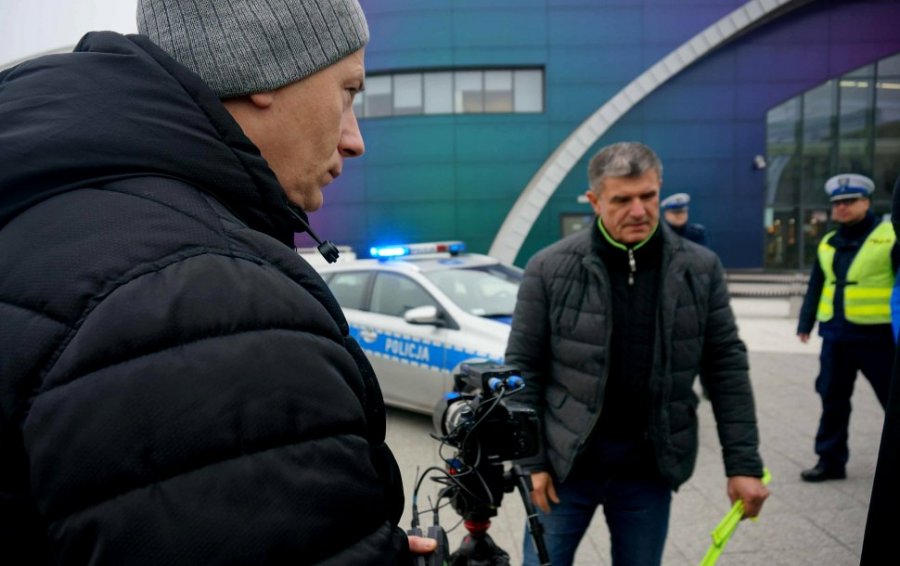 Dwaj mężczyźni w tle radiowóz i policjant