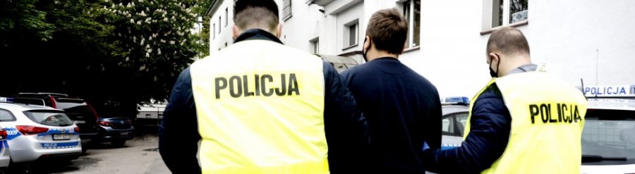 dwaj policjanci prowadzą zatrzymanego mężczyznę