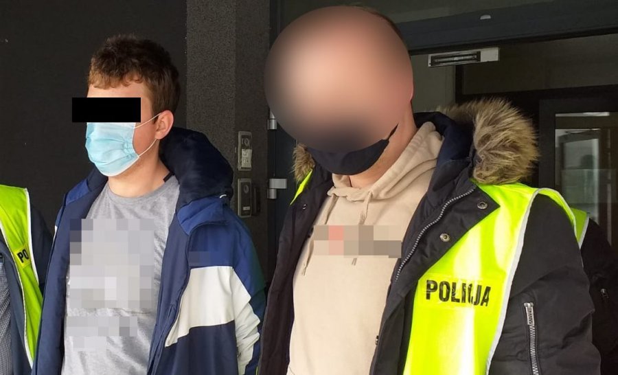 Zatrzymany mężczyzna prowadzony przez policjantów w żółtych kamizelkach z napisem Policja