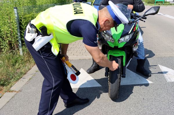 Policjant sprawdza stan bieżnika w skuterze.