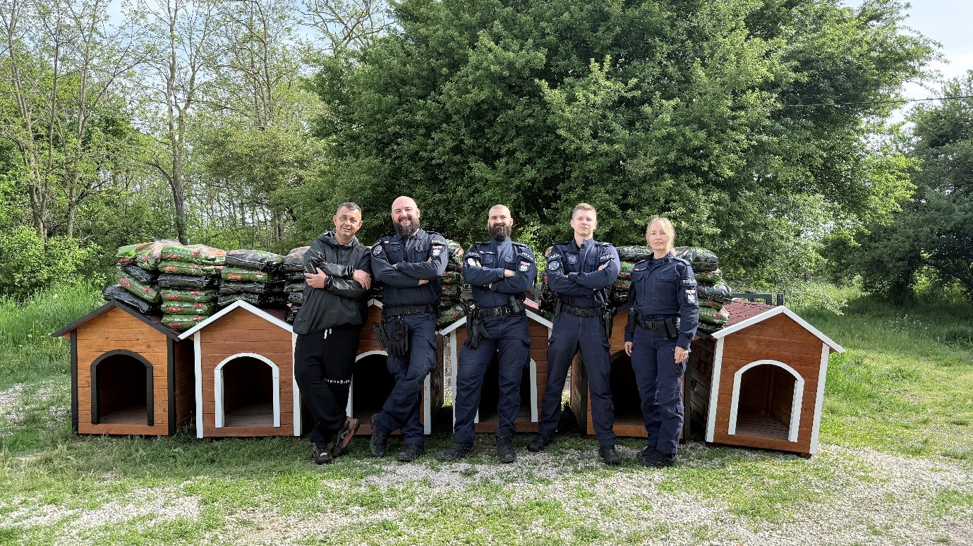 Policjanci w Kosowie przy budach na których lezy karma dla psów.