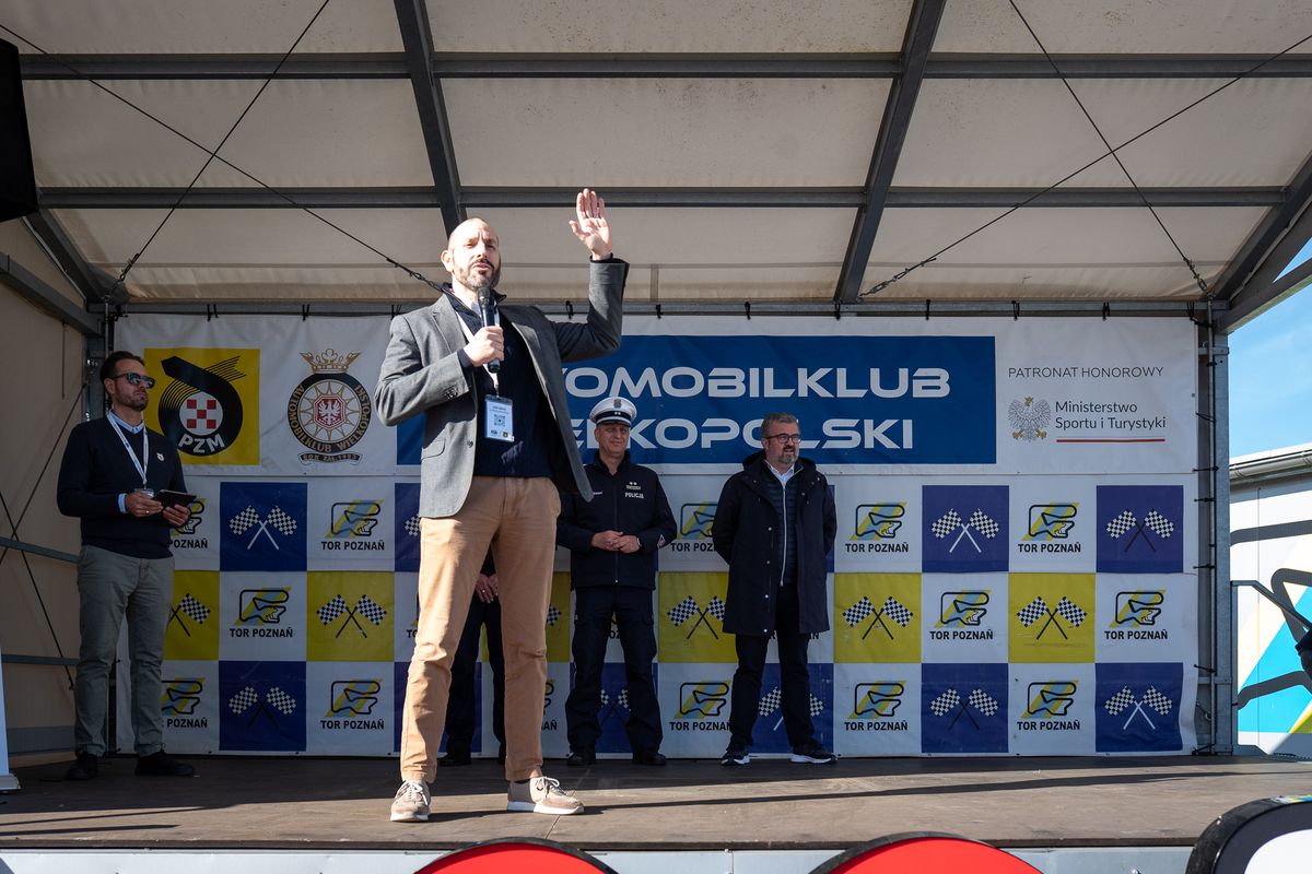 Mężczyzna mówiący przez mikrofon na scenie.