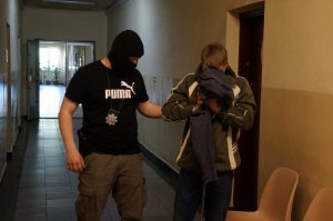 Policjant prowadzi zatrzymanego
