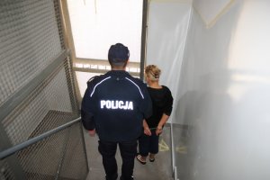 Policjant prowadzi zatrzymaną kobietę