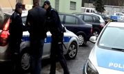 Zatrzymany prowadzony przez policjantów do radiowozu