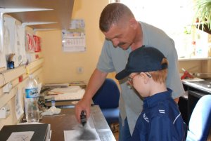 technik kryminalistyki pokazuje chłopcu jak ujawnia ślady linii papilarnych