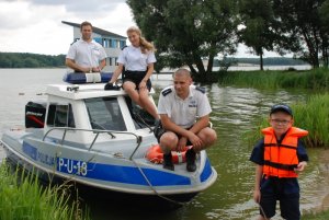 chłopiec w kamizelca ratunkowej w towarzystwie patrolu policji na łodzi motorowej