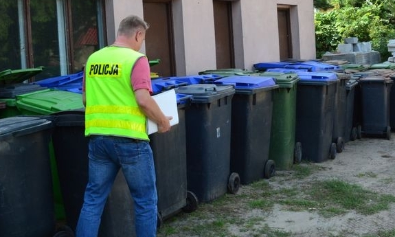 Policjant z odzyskanymi koszami na śmieci