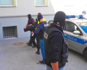 Policjanci prowadzą jednego z zatrzymanych