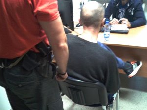 Zatrzymany przesłuchiwany przez policjanta