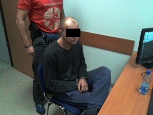 Zatrzymany przesłuchiwany przez policjanta