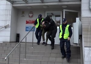 Policjanci wyprowadzają zatrzymanego