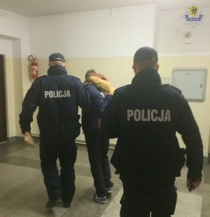 Policjanci prowadzą zatrzymanego