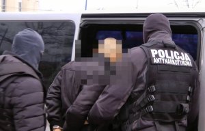 Policjanci prowadzą zatrzymanego