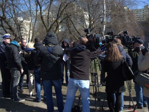 dziennikarze z kamerami i policjant w tle