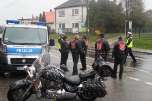 na pierwszym planie motocykl, potem radiowóz, motocykliści i policjanci