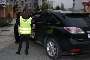 skradziony pojazd widok z lewego tyłu i stojąca przy nim policjantka