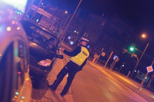policjant nocą bada trzeźwość kierowcy