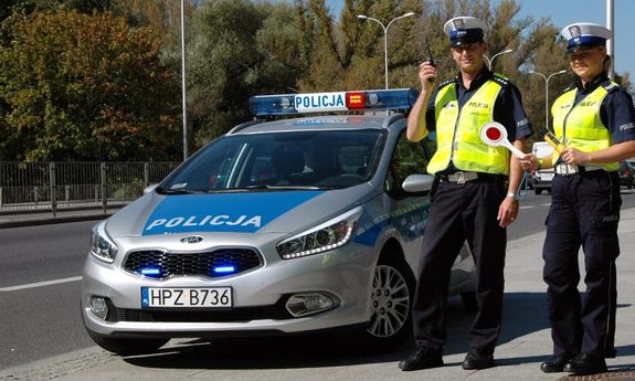 Policjanci ruchu drogowego przy radiowozie na drodze