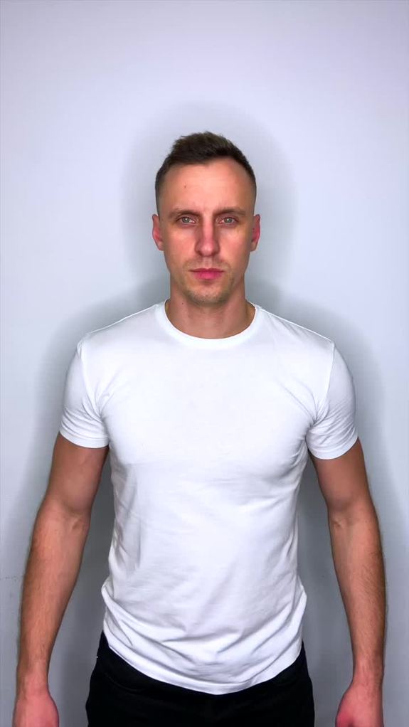 Mężczyzna w białej koszulce na tle szarej ściany.
