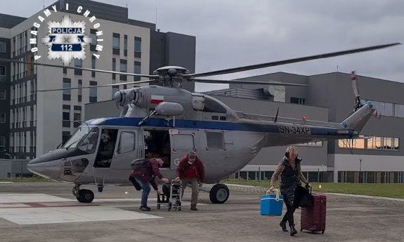 Śmigłowiec Sokół na lądowisku z którego wychodzą trzy osoby.