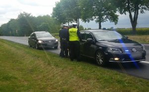 policjanci przy radiowozie zatrzymują prowadzącego skradzione auto