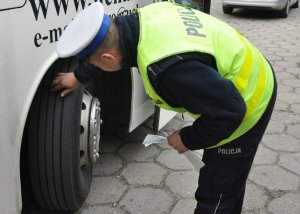 policjant sprawdza stan ogumienia pojazdu