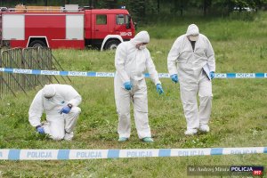 Policjanci w strojach ochronnych badają teren