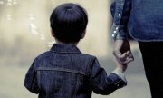 Dziecko idące z dorosłym, trzymające go za rękę