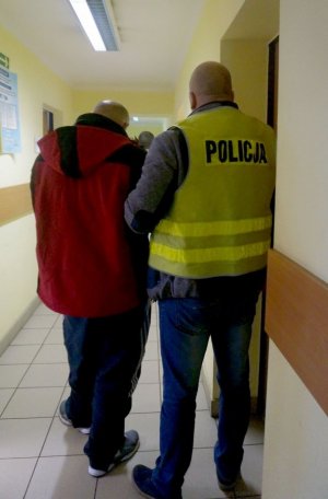 policjant prowadzi zatrzymanego