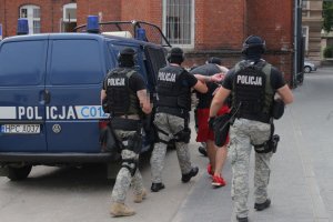 policjanci prowadzą jednego z zatrzymanych