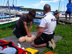 uczestnik pod okiem policjanta ćwiczy resuscytację