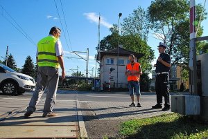 policjant i pracownicy kolei na przejeździe